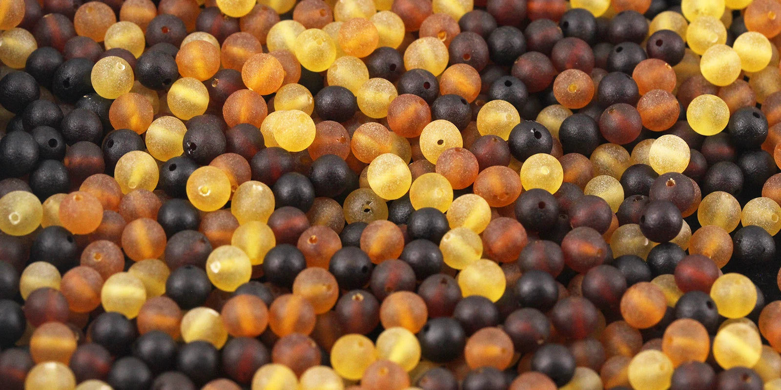Close-up of multicolored amber loose beads in shades of yellow, orange, and black.